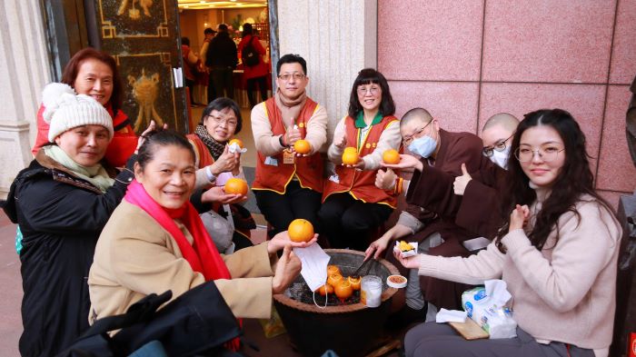《圖說》與法師圍爐烤橘子、話家常，是靈鷲山獨有的暖心年味活動。〈靈鷲山佛教教團提供〉