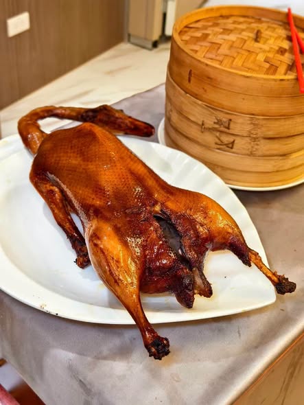 片製招牌片皮鵝，搭配蔥段、小黃瓜與特製甜麵醬，以薄餅包裹入口，酥脆鴨皮與鮮嫩鵝肉交織，展現道地粵式片皮料理的層次風味。圖／周含鍾攝